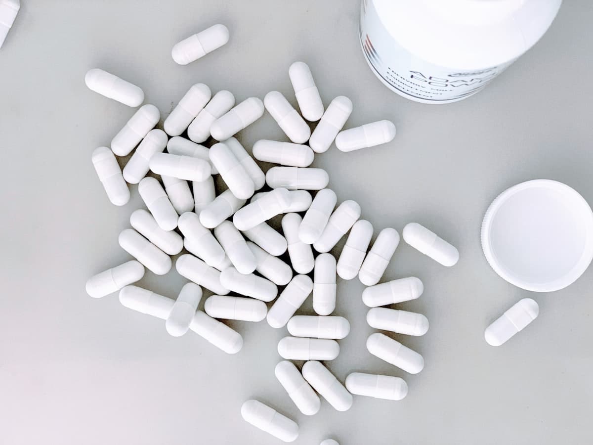 White probiotic capsules spilling from a supplement bottle on a light surface — how many of the labeled CFUs survive stomach acid