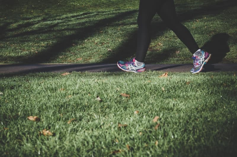 Woman brisk walking outdoors on a scenic trail — steady-state LISS cardio example