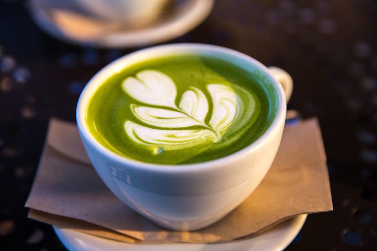 Matcha powder and coffee cup side by side on a wooden table — which is healthier?