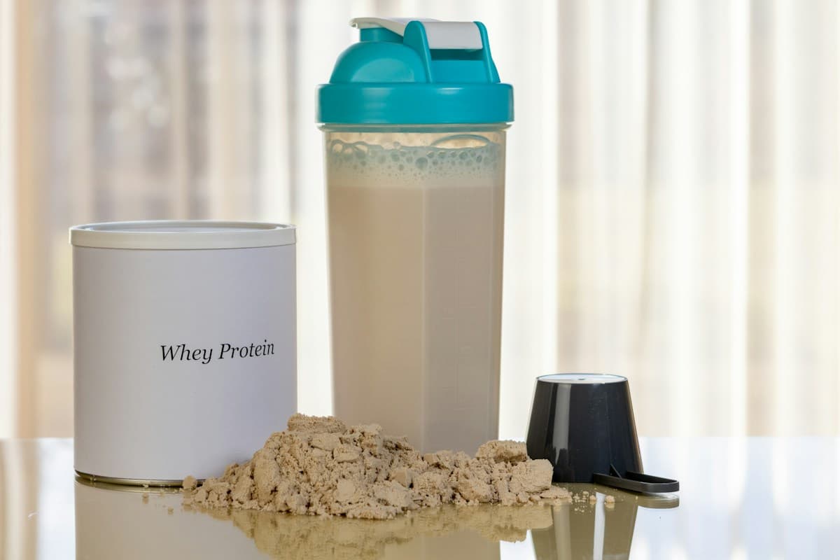 Whey protein powder with a scoop and shaker bottle on a table