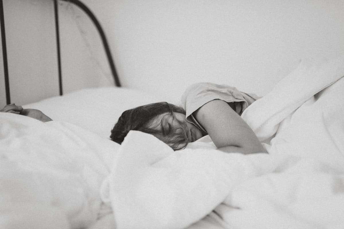 Person wearing a sleep mask in bed — how direct light blocking improves sleep quality and melatonin production