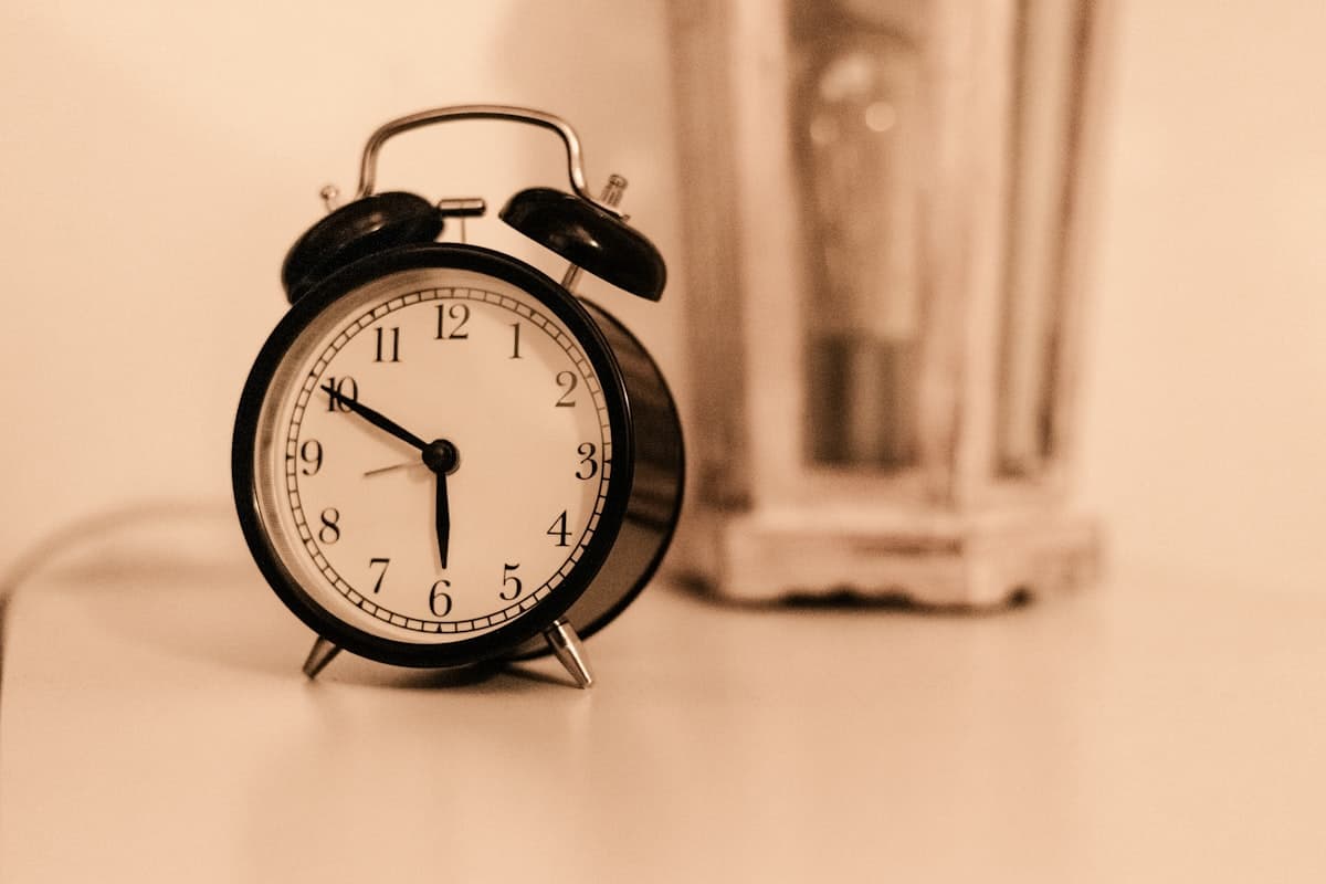 Classic twin-bell alarm clock on a bedside table in a dark bedroom, symbolizing 3 AM wake-ups from NMN taken at night