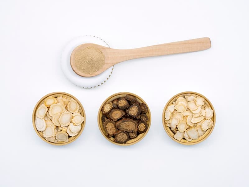 Bowls of dried herbal powder with a wooden spoon on a white surface, illustrating the dose, timing, and extract dials for reducing ashwagandha dreams