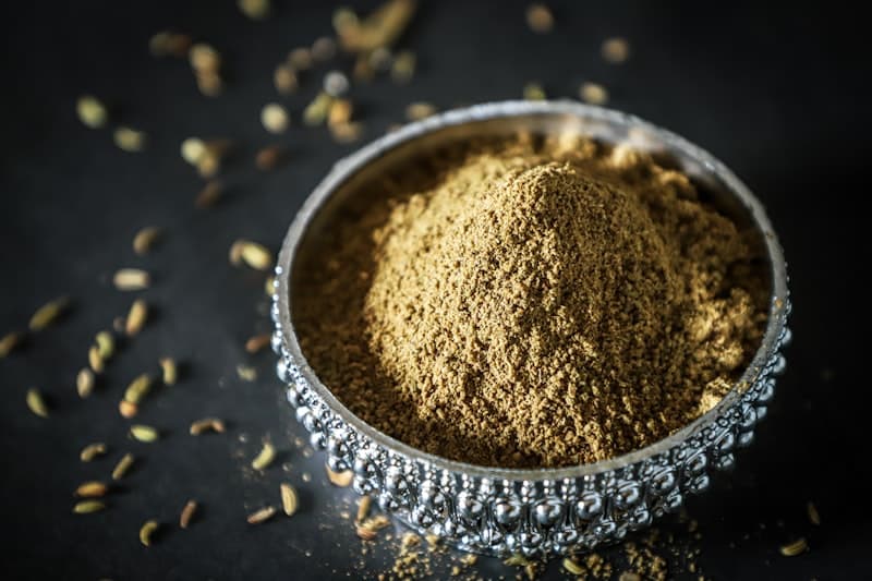 Brown ashwagandha root powder in a silver bowl